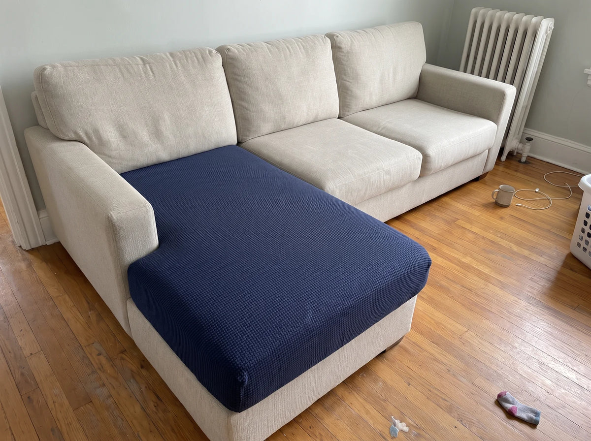 A navy blue Avelo Casa cover stretched flat over a chaise cushion, with the elastic tucked underneath