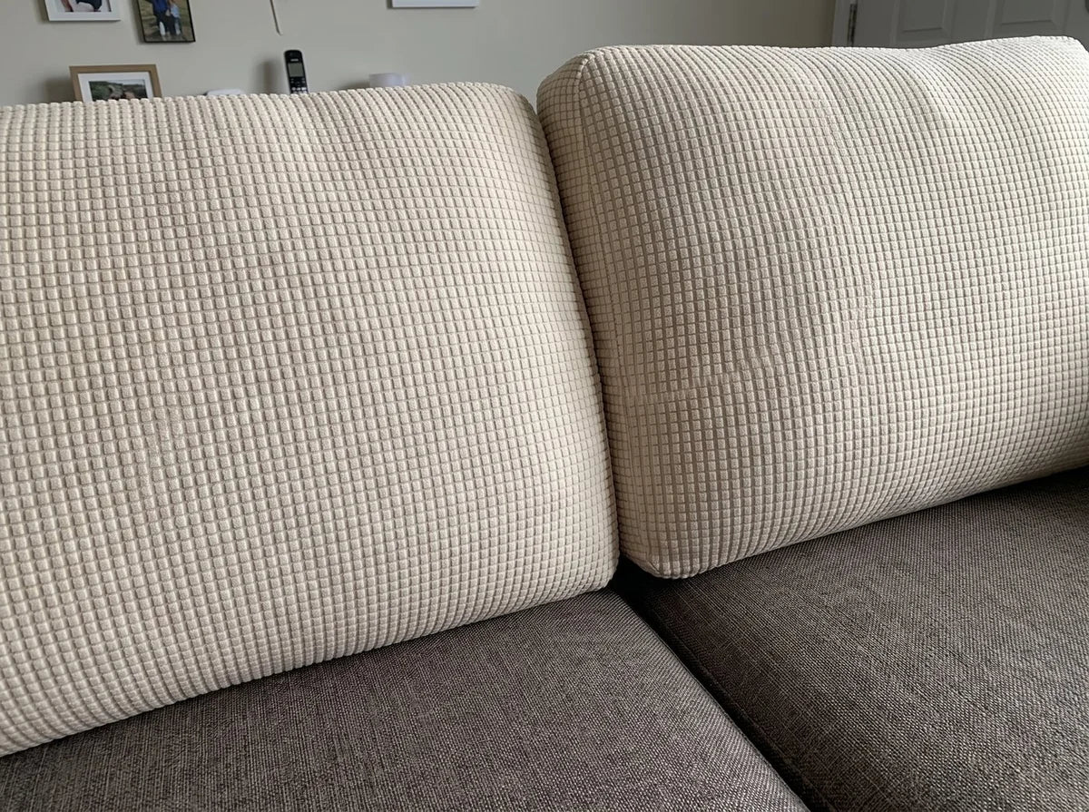 Two sofa back cushions fitted with cream Avelo Casa covers over a darker uncovered sofa