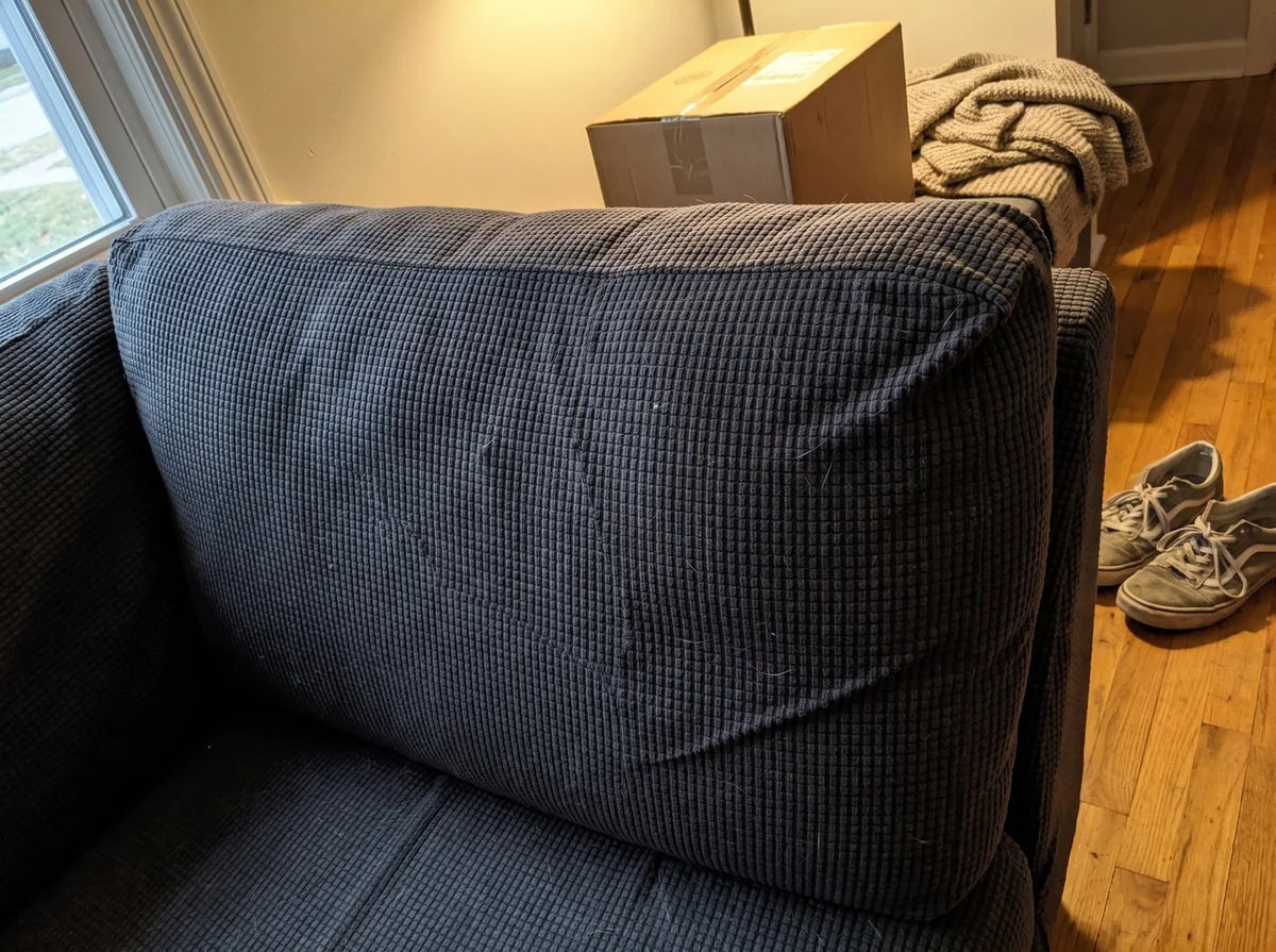 A sofa back cushion fitted with a dark grey Avelo Casa cover in a lived in room